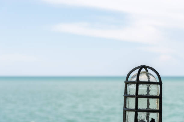 Old vintage lamp near the harbour with the sea view in the summer time.