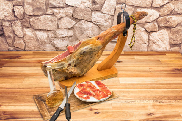 spanish serrano ham on the leg with wood holder on a table - serrano chilli pepper meat ham spain imagens e fotografias de stock