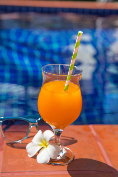 istock Orange juice with sunglasses on swimming pool border 913326422