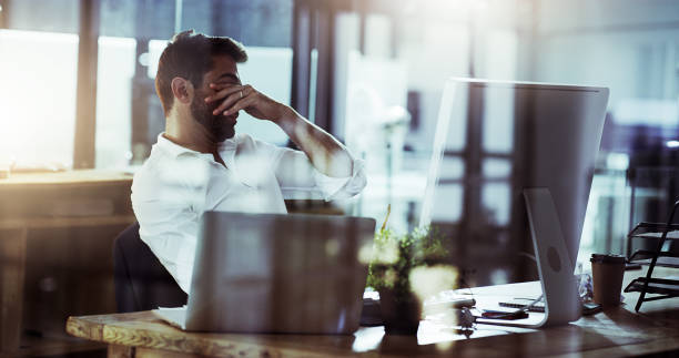 These late nights are killing me Cropped shot of a young businessman looking stressed while working late in the office overworked stock pictures, royalty-free photos & images