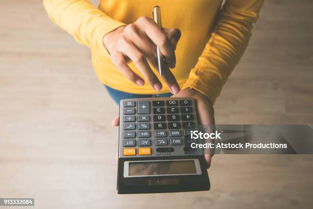 Donna Che Usa Una Calcolatrice Con Una Penna In Mano - Fotografie stock e altre immagini di Calcolatrice