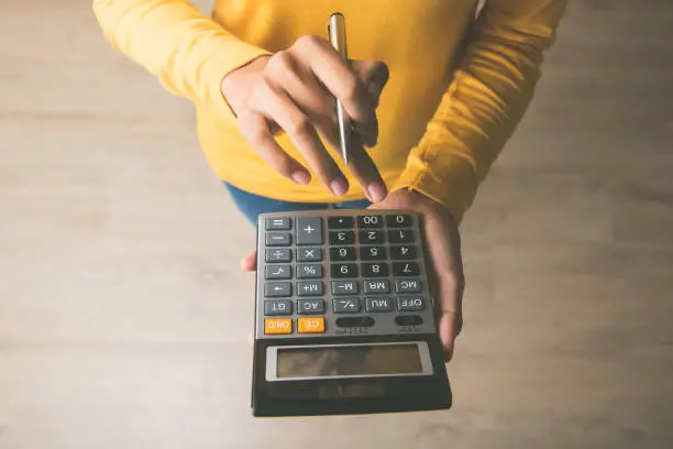 Photo of Woman using a calculator with a pen in her hand