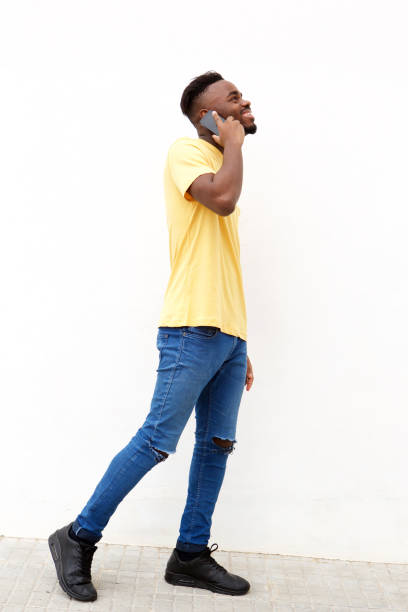 istock Full length young black man talking on cellphone against white wall 913338242