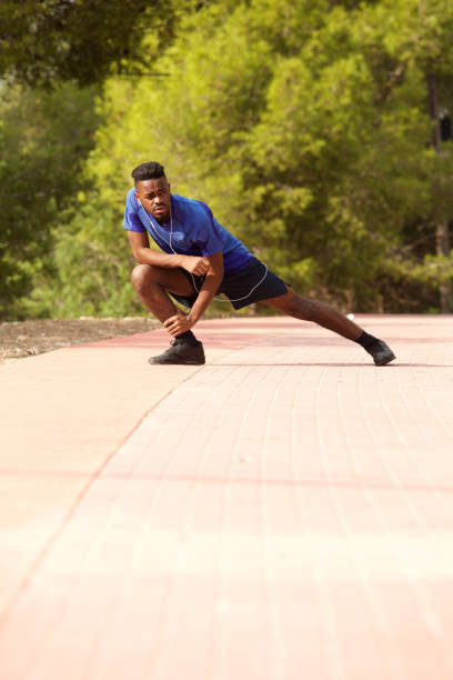 istock Full length sporty black man doing exercise stretches outside 913338418
