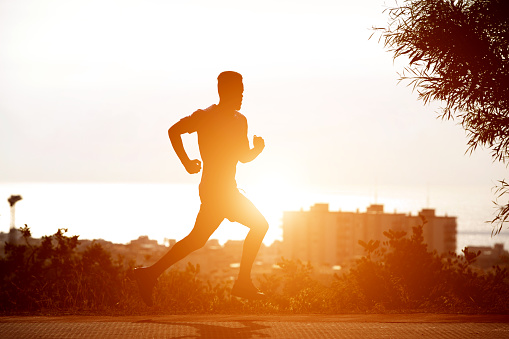 Silhouette of young black man running in sunset