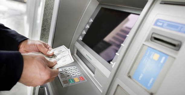 istock Man counting currency at ATM 913342748