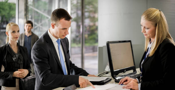 istock Female bank teller helping male customer with documents he needs to sign 913342786
