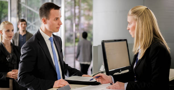 istock Female bank teller helping male customer with documents he needs to sign 913342812