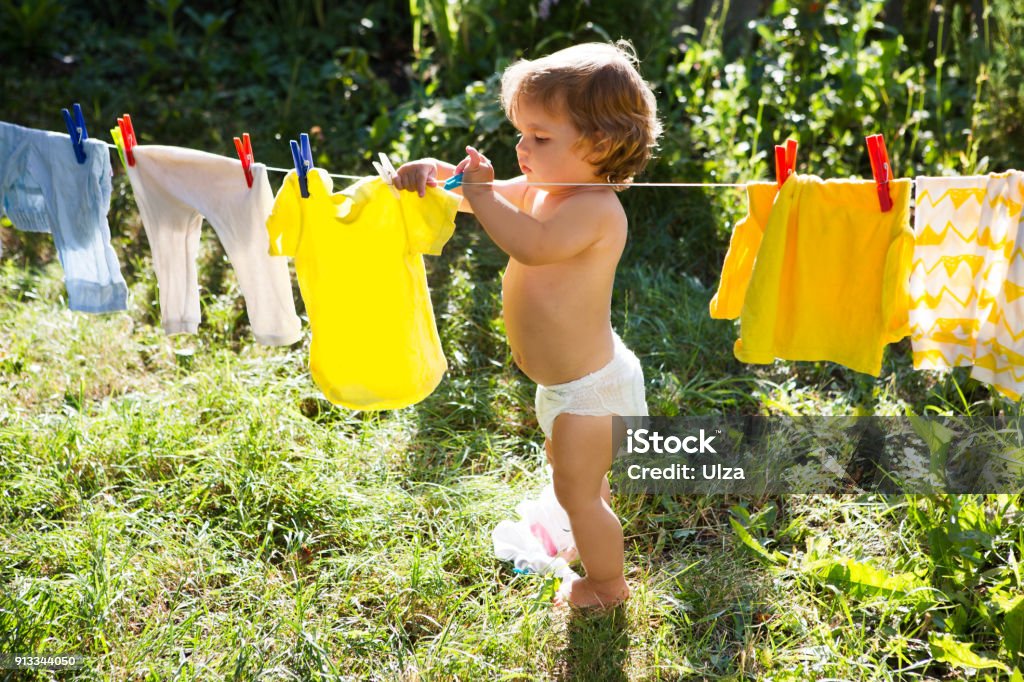 fun happy baby girl to wash clothes and laughs  in the meadow on a sunny summer day Baby - Human Age Stock Photo