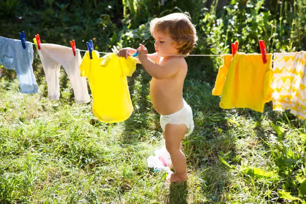 Photo of fun happy baby girl to wash clothes and laughs  in the meadow on a sunny summer day