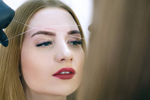istock Close-up of female face during eyebrow correction procedure 913346338