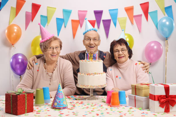 istock Happy seniors with a cake and party hats 913346848