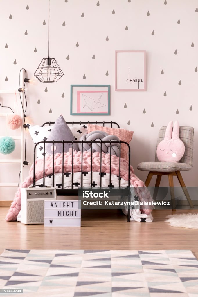 Girl's pastel bedroom interior Pink knit blanket on girl's bed against the wall with posters in pastel bedroom interior with chair Bedroom Stock Photo