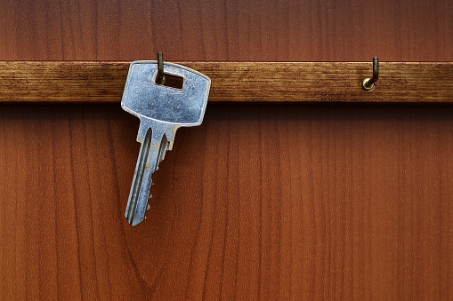 Old key hanging against a wooden background