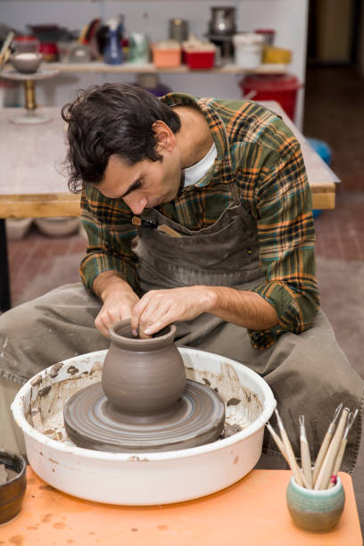 istock Artist makes clay pottery on a spin wheel in workshop 913358196