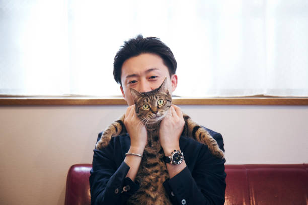 Japanese man holding his cat on the sofa.