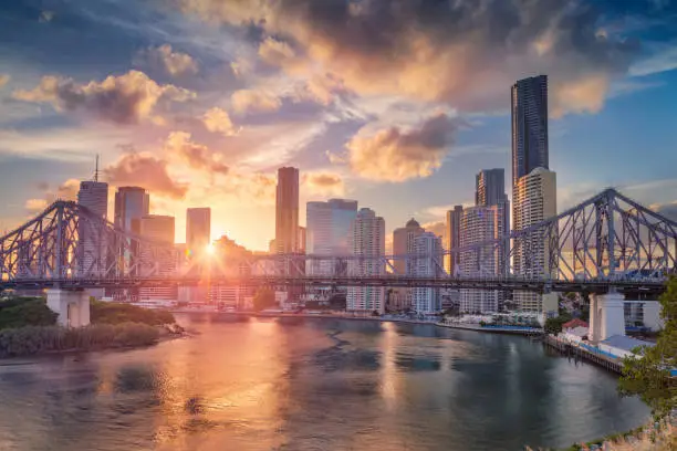 Cityscape image of Brisbane skyline, Australia with Story Bridge during dramatic sunset.