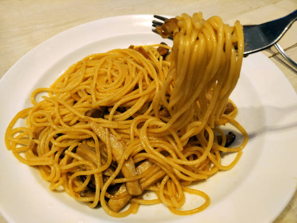 istock Close up mushroom spaghetti with fork holding up the food 913363776