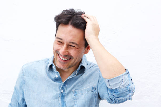 mature guy smiling with hand on head against white background - hand in hair imagens e fotografias de stock