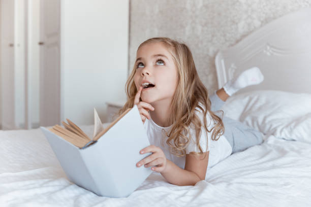 istock smiling kid lying on bed with book and looking up 913382274