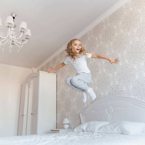 istock smiling child jumping on bed and looking at camera 913386860