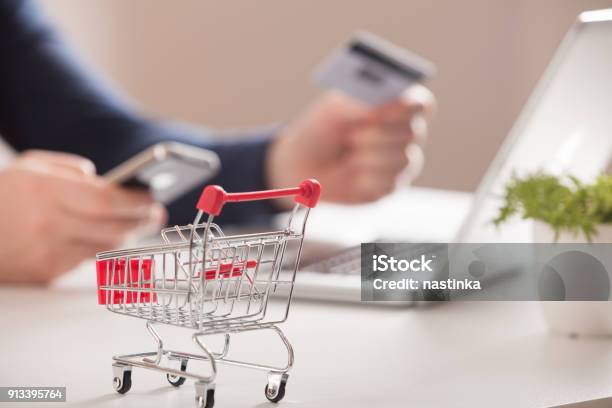 Bank Card Nearby A Laptop And Mini Shopping Cart On White Background Top View Stock Photo - Download Image Now
