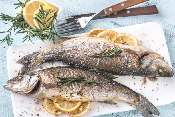 baked sea bass with lemon and rosemary - prepared fish fish grilled close up imagens e fotografias de stock