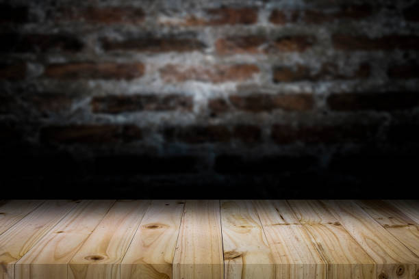 istock Wood table top on old dark brick wall background. 913415062