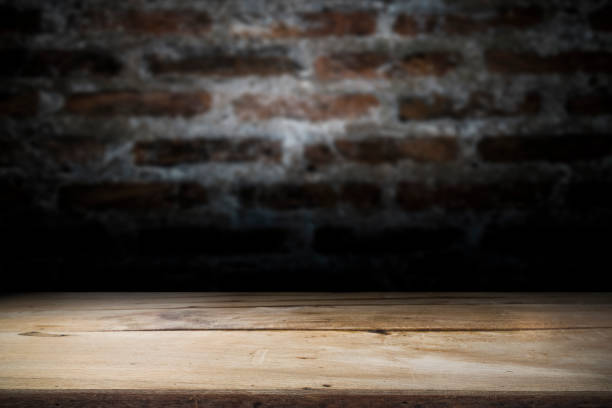 istock Wood table top on old dark brick wall background. 913415072