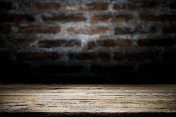 istock Wood table top on old dark brick wall background. 913415080