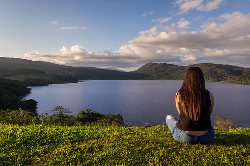 young woman sitting at the top of a hill overlooking Cote lake taking in the serene and natural beauty of the area