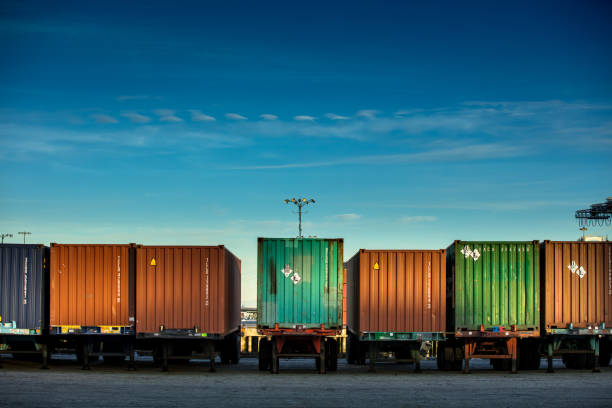 Line of Shipping Containers on Trucks Rear view of a line of trucks loaded with differently colored shipping containers. cargo container shipping harbor trading stock pictures, royalty-free photos & images