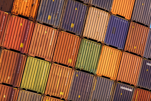 Angle shot of multicolored shipping containers stacked together.