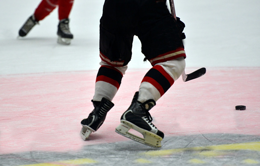 Male icehockey player on the ice with the puck inside an icehockey arena