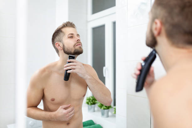 istock Handsome bearded man trimming his beard with a trimmer 913432380