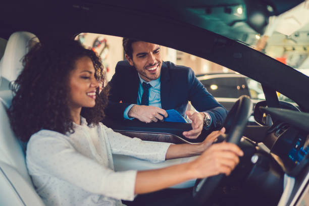 Mixed race woman enjoying new car Smiling woman in the showroom enjoying luxury car driving test photos stock pictures, royalty-free photos & images