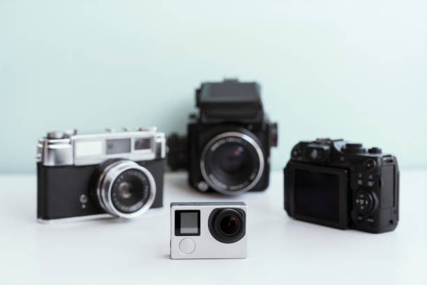 Brand new action camera with vintage cameras on the background, Studio shot