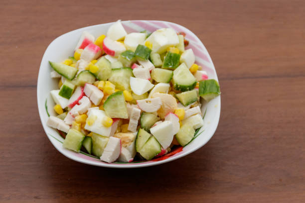 istock Salad with crab sticks, sweet corn, cucumber and eggs on wooden table 913465978