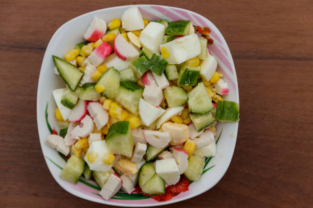istock Salad with crab sticks, sweet corn, cucumber and eggs on wooden table 913465980