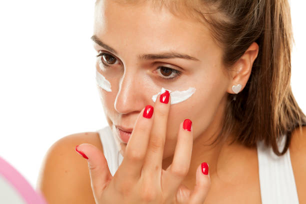 istock young woman applying cream to her face 913475432