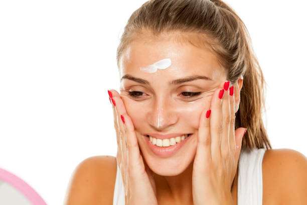 istock young woman applying cream to her face 913475464