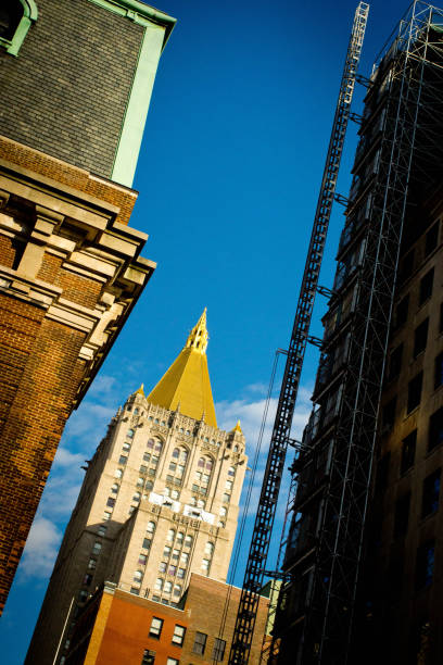 New York Life Building New York Life Building viewed through high rise buildings and a construction lift for a new skyscraper on the right. new york life building stock pictures, royalty-free photos & images