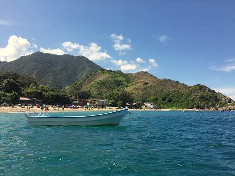 Empty boat anchored in coastline, in front of a beach. Caribbean sea. Copy space. Profile view. Scenic image. Tropical climate. Sunny day.