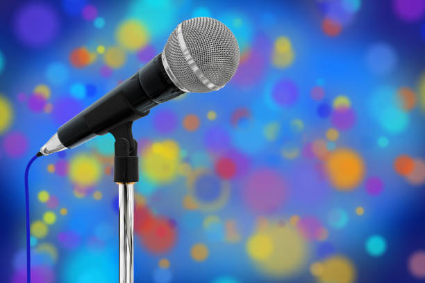 istock Composite close up of a cardioid dynamic ball head microphone on a microphone stand in the background there are multi coloured particles on a blue background with a vignette. 913492886