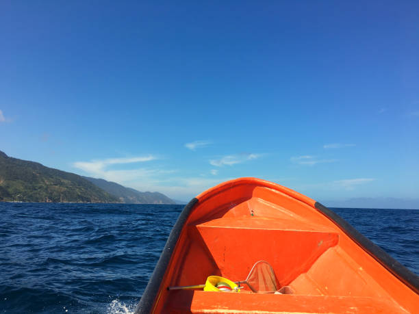 Bow of an orange boat sailing in the coastline. No people. Caribbean sea. Copy space. Front view. Scenic image. Tropical climate. Sunny day.