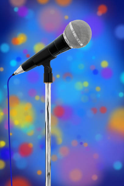 istock Composite close up of a cardioid dynamic ball head microphone on a microphone stand in the background there are multi coloured particles on a blue background with a vignette. 913492968