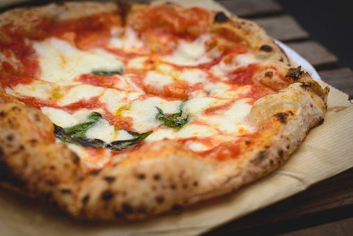 Close up view of a Margherita Neapolitan style pizza with buffalo mozzarella, tomato sauce and basil. Landscape format.