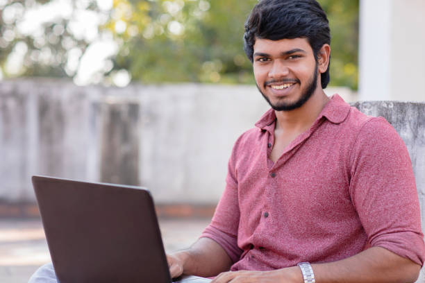 istock Smiling young man with laptop 913497506