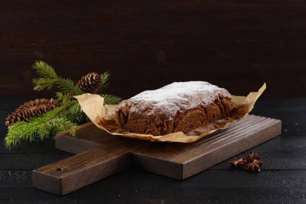 Tasty freshly baked fruit cake with fir btanch on dark background copy space