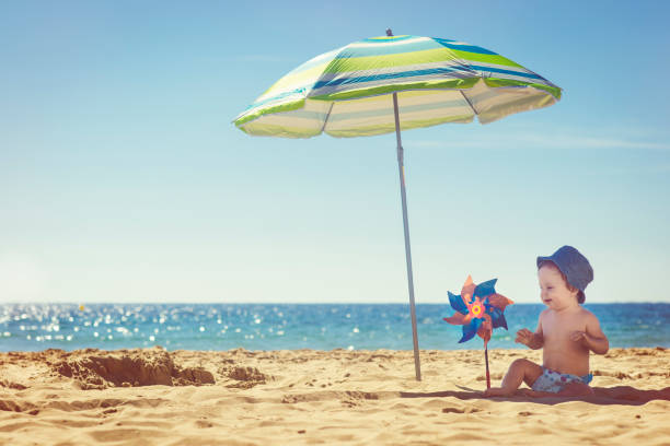Cute baby with toy windmill on the beach